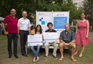 CeNS Innovation Nano, woman and man posing with checks alongside others at a park