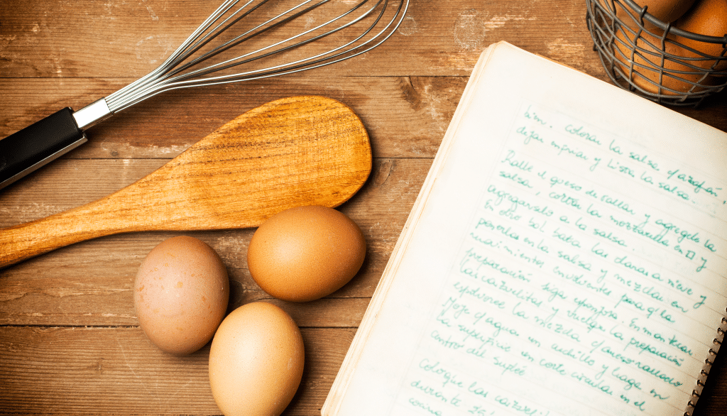 Recipe on paper next to eggs, spoon, spatula on wooden table featured image