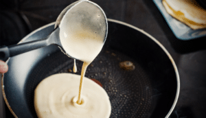 Pouring pancake batter into greased cooking pan featured image