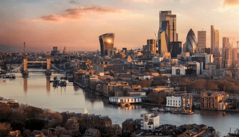 Sun setting over tall London buildings and the nearby, reflective water