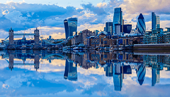 Blue hue over tall London buildings and the nearby, reflective water